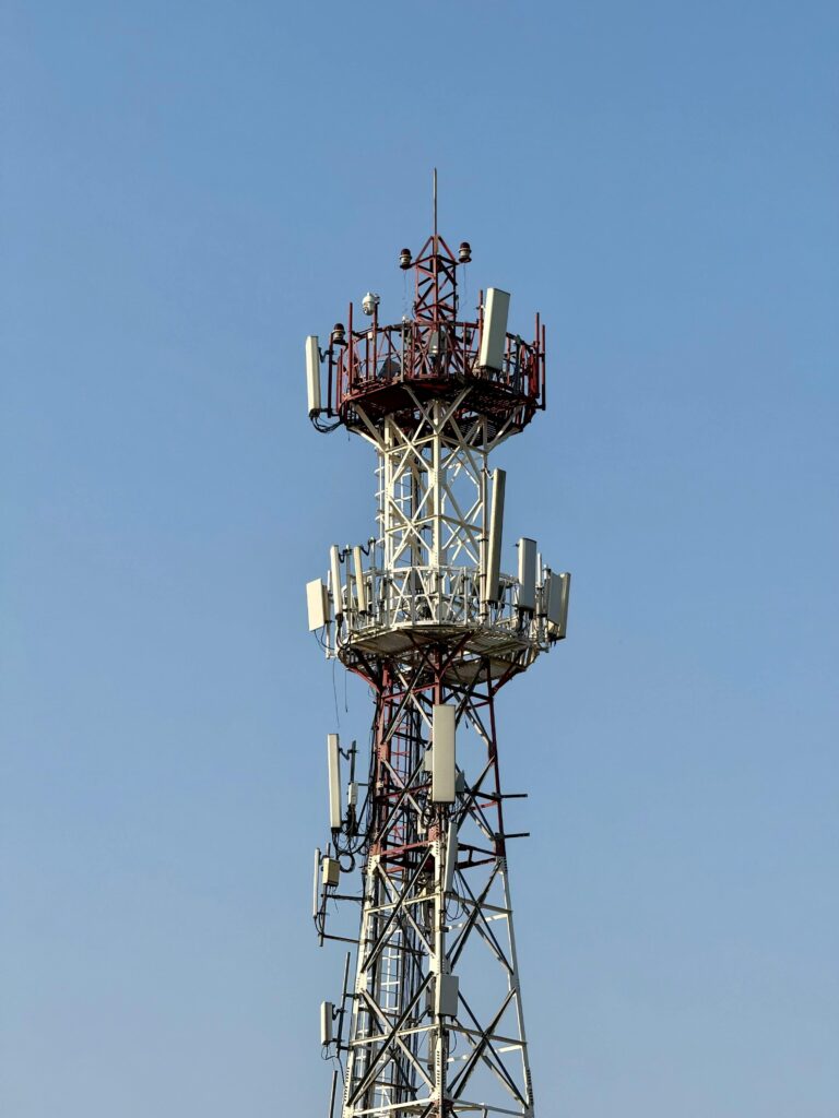 A tall telecommunication tower with multiple antennas against a clear blue sky, representing technology and communication.