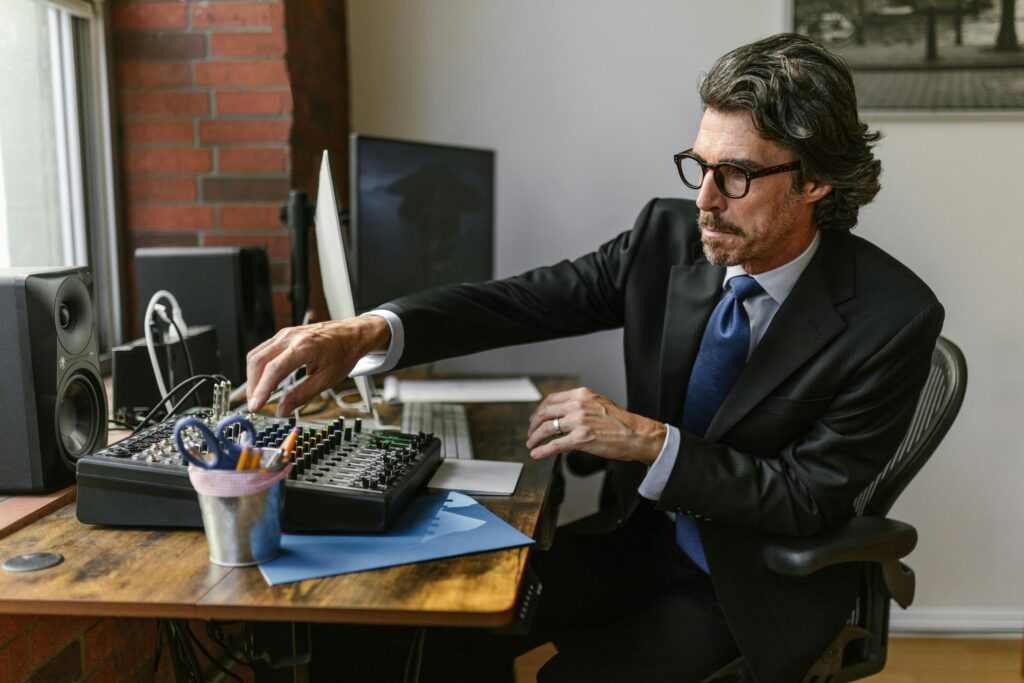 Elderly man in suit working with audio mixer in modern office setting.